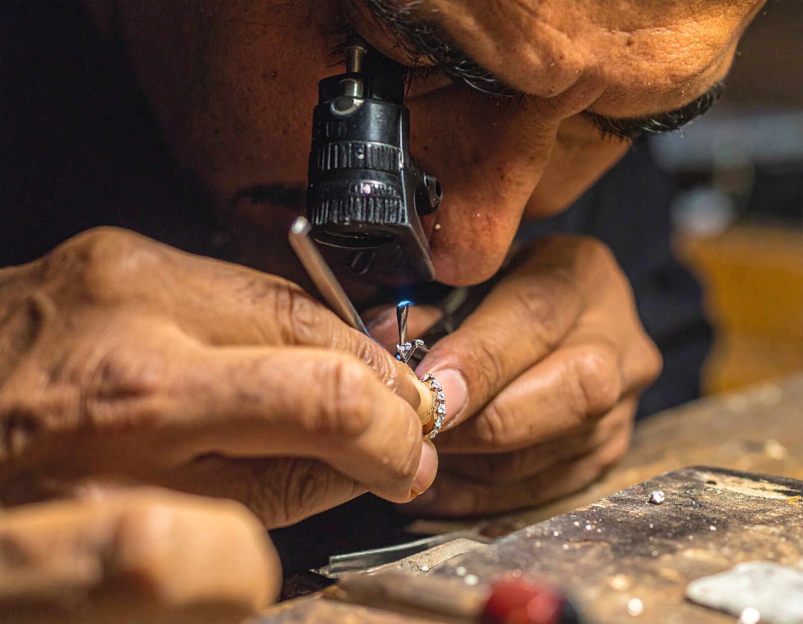 Jeweller setting a diamond into a ring by hand under a loupe
